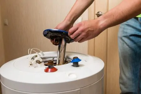 Man opening the lid of a water heater to check for problems