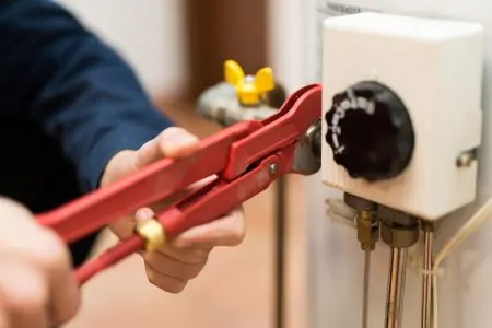 Man adjusting a fitting in the water heater panel
