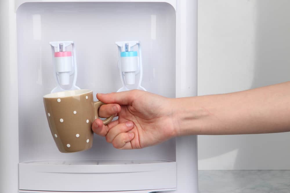 Woman filling cup at best hot water dispenser