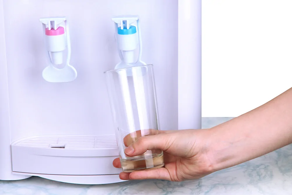 Woman filling cup at water cooler dispenser