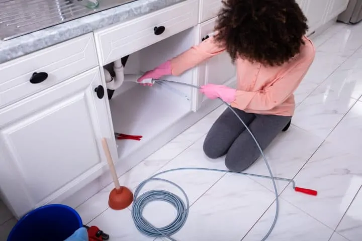 Woman Cleaning Clogged Sink Pipe