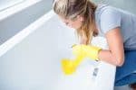 woman removing hard water stains from bathtub