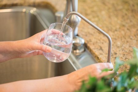 Woman getting reverse osmosis water from tap