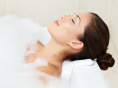 Woman in a bathtub leaning on a bath pillow