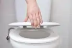 Woman closing the toilet seat