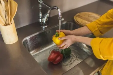 Woman washing vegetables on the sink
