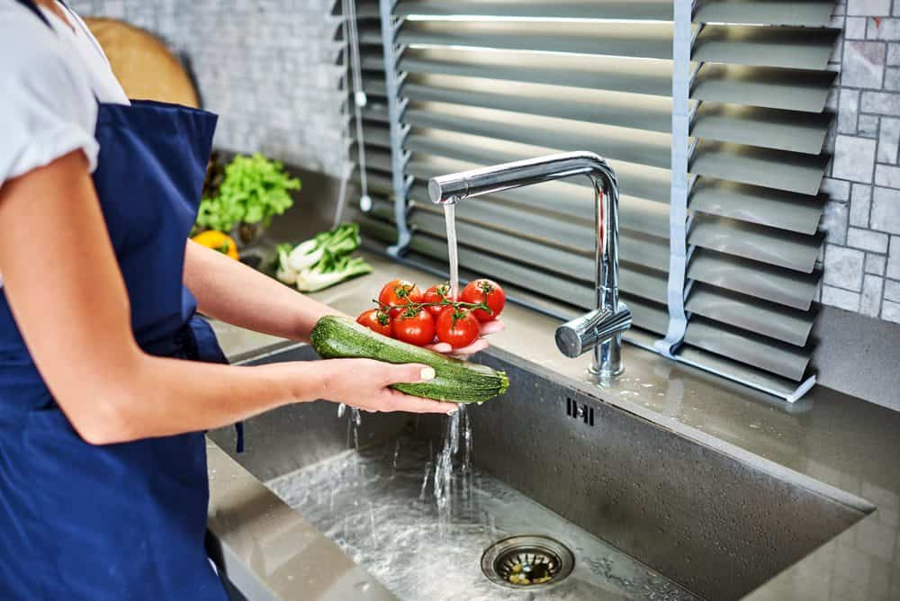 Woman washing vegetables in an undermount kitchen sink