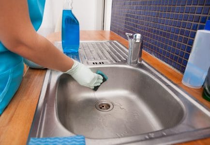 Woman cleaning a stainless steel sink