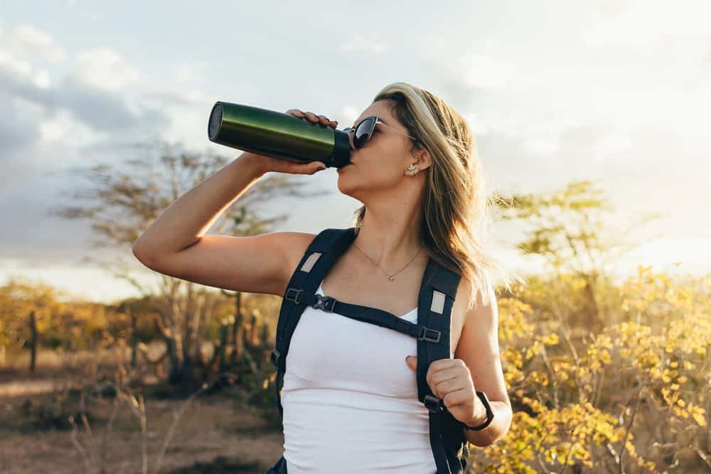 Woman drinking from a water bottle during a hike
