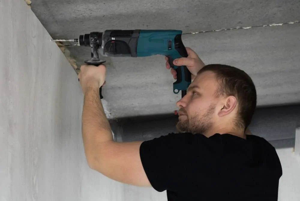 Man drilling into concrete wall with a hammer drill