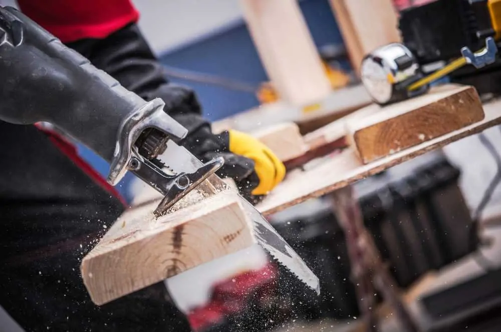 Carpenter cutting through wood with reciprocating saw blade