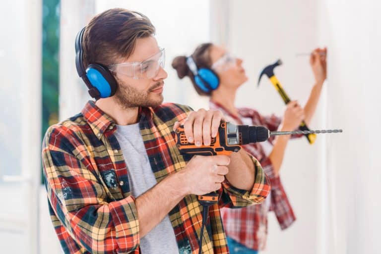 Man drilling into a wall with a corded hammer drill