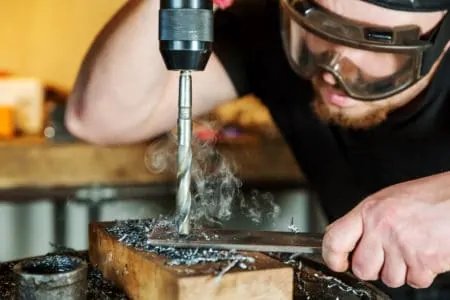 Man drilling through metal with an electric drill