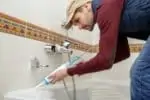 Man applying bathtub caulk