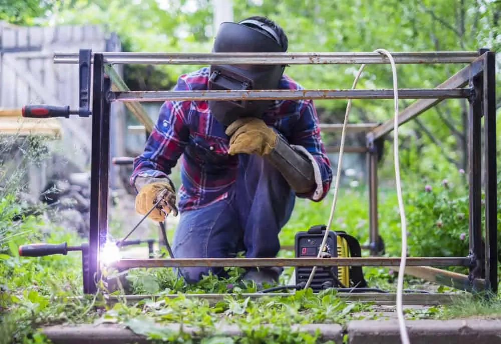 Man in a protective mask welding metal construction outside