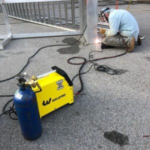 Man welding a fence with a 110 volt welder