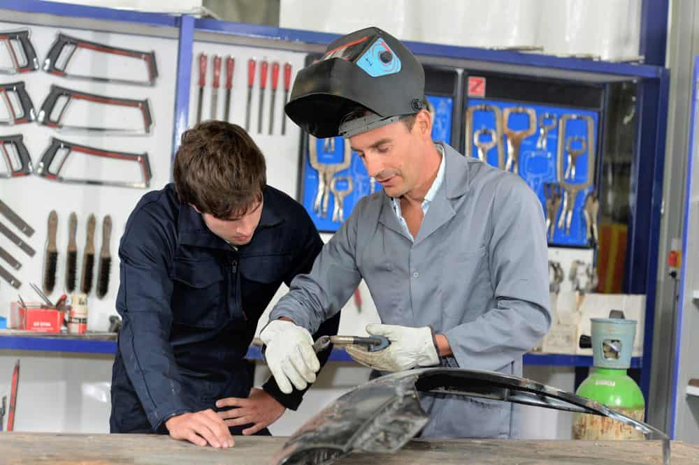 Trainee with instructor using welding machine