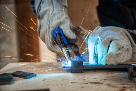 Man with welding gloves holding a gas torch