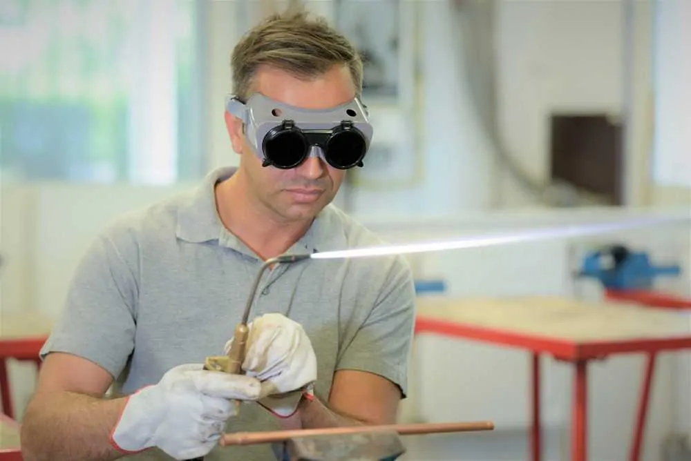 Man wearing welding goggles while using a gas torch