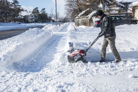 Man clearing snow with a cordless snow blower