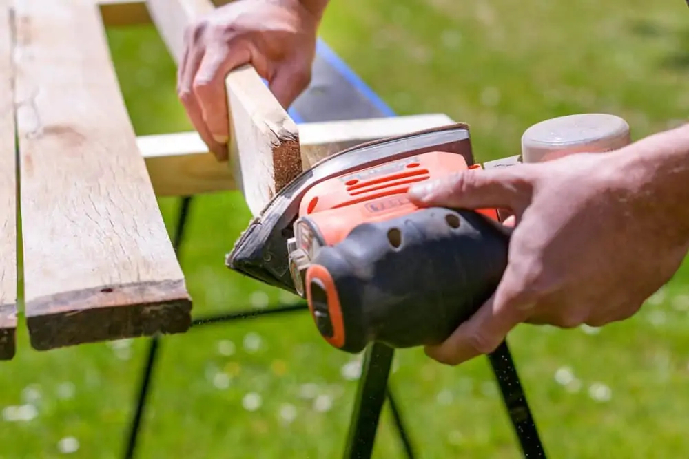 Sanding wooden stool with a detail sander