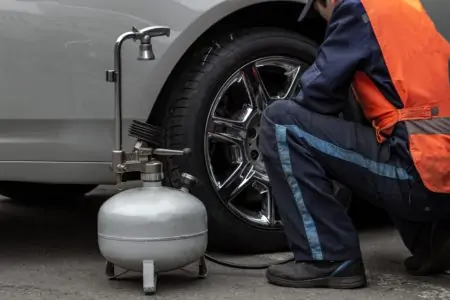 Man inflating car tire with a pancake air compressor