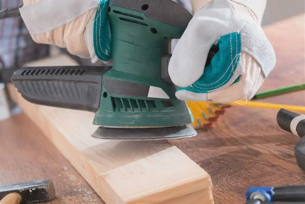 Sanding plank of wood with orbital sander