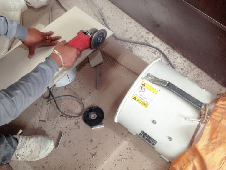 Woodworker cutting wood with a grinder and a dust collector on the side