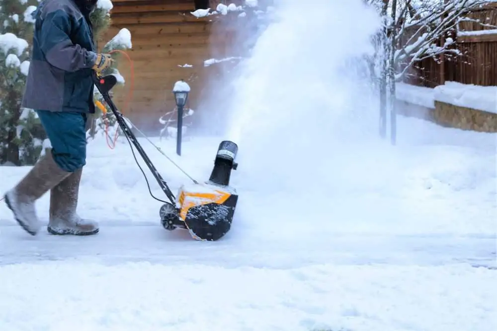 Man clearing snow with electric snow blower