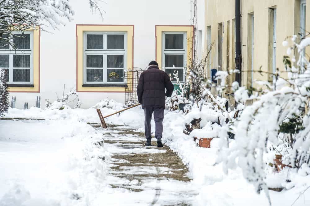 私道から雪を掃除する男