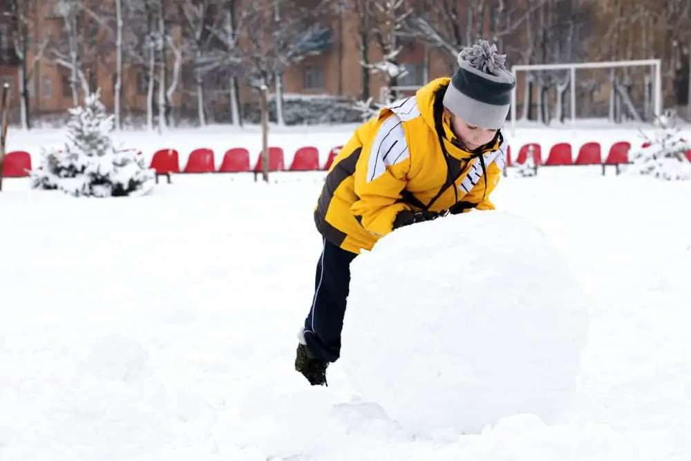 Kid rolling snow to make snowman