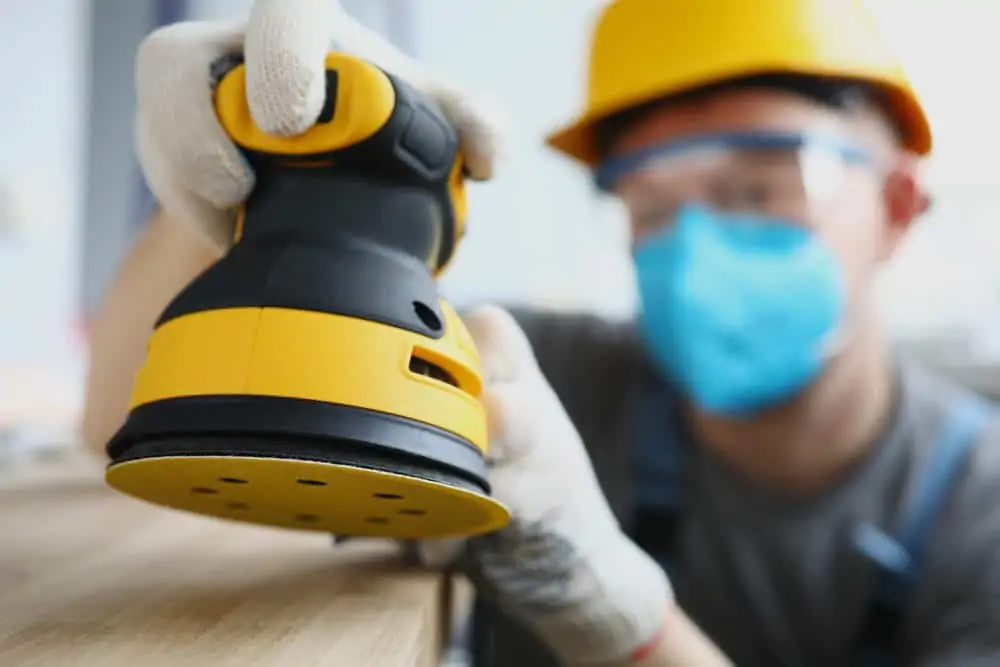 Man sanding table with orbital sander