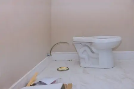 Plumber installing toilet bowl seat in restroom