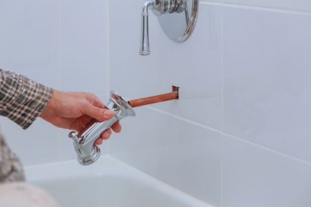 Plumber holding a faucet over bathtub