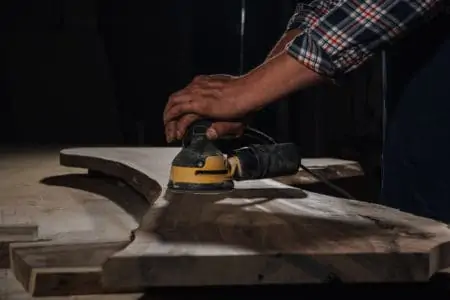 Person sanding wood with orbital sander
