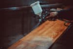 Master painter in a factory - industrial painting wood with spray gun