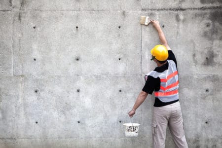 Painter working on an old concrete wall