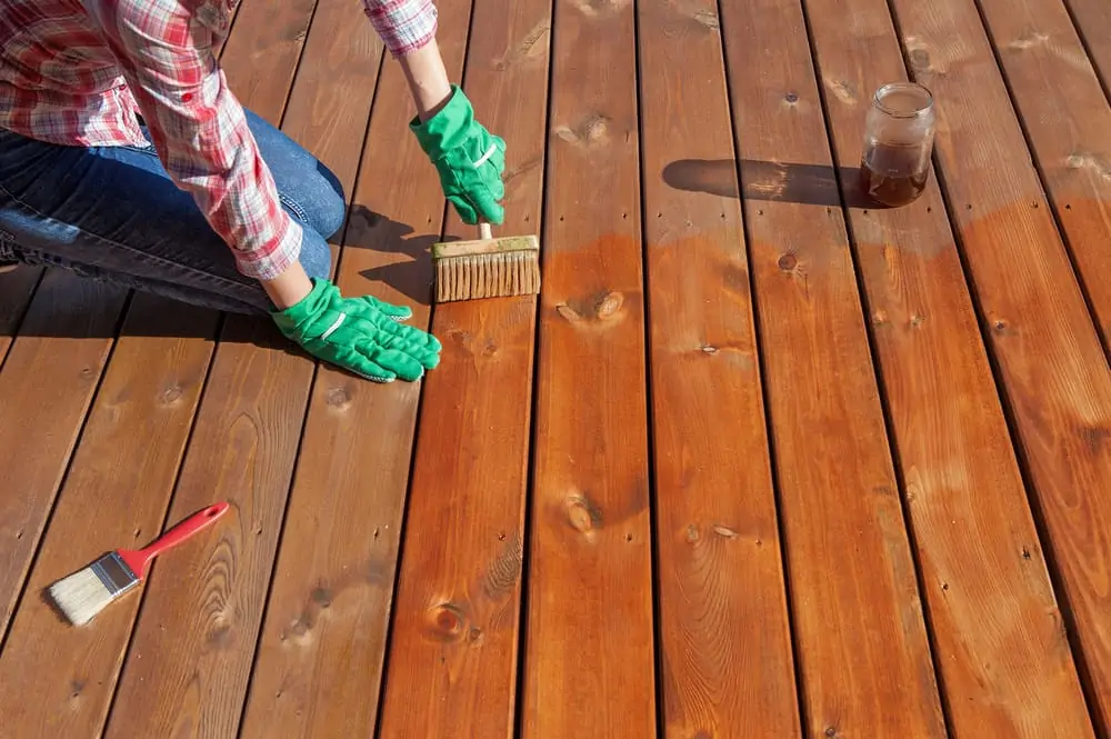 Person applying varnish on a wooden deck