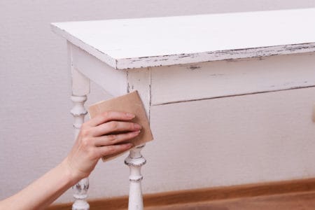 Female hand removing paint from wooden tabel