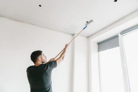 Man painting a ceiling with a roller