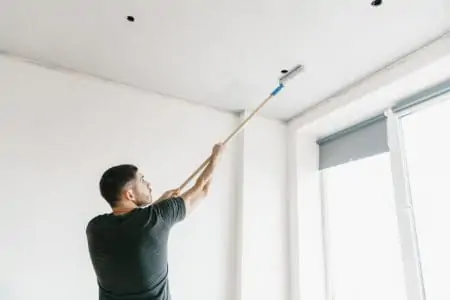 Man painting a ceiling with a roller