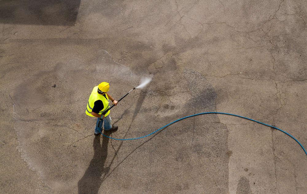 Worker pressure washing concrete floor
