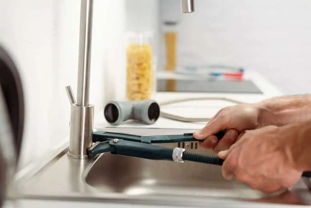 Man tightening a kitchen faucet with a wrench