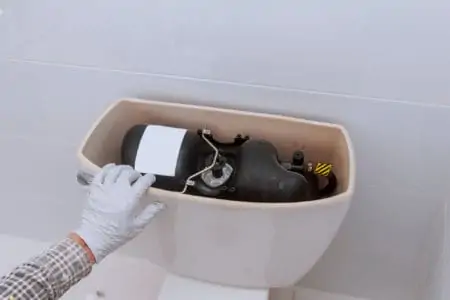 Plumber repairing an open toilet tank