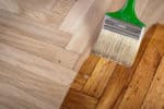 Varnishing hardwood floor with a paint brush