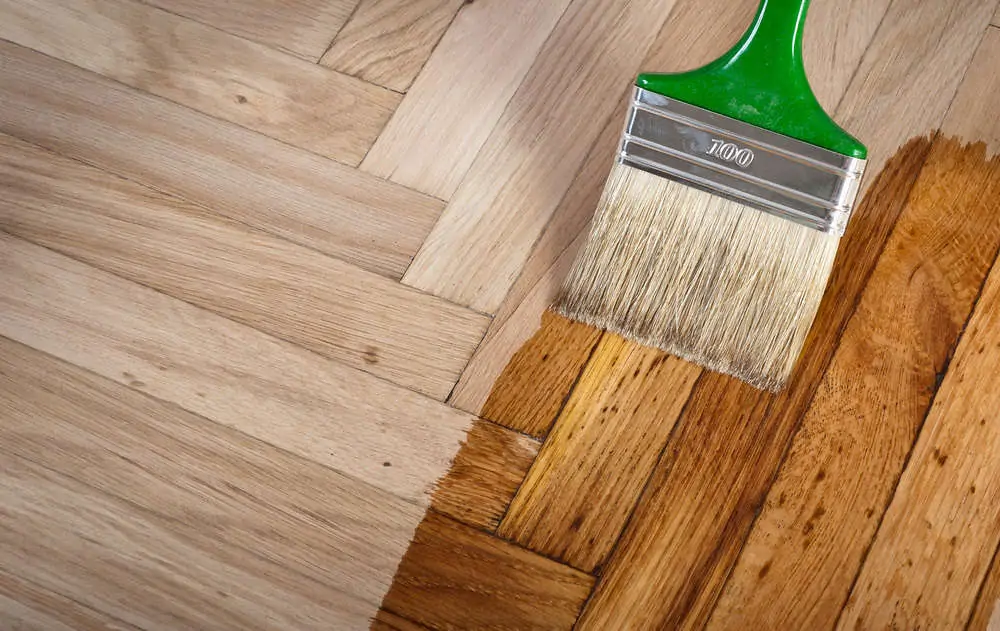 Varnishing hardwood floor with a paint brush