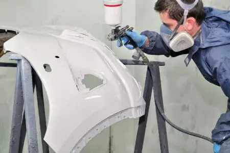 Professional painting car bumper with a spray gun