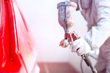 Worker painting a car with spray gun