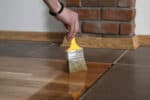 Person treating hardwood with a paint brush