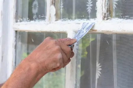 Close up male hands make putty works. Repairing wood window for protection, warterproof